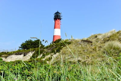 Lighthouse on field against sky