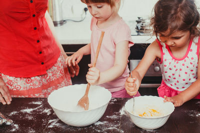 Cute girls preparing batter of cookies at home