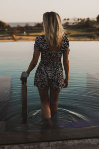 Rear view of woman standing in sea against sky