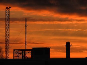 Silhouette tower against orange sky