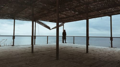 Rear view of woman standing in gazebo by sea