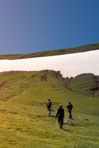 Rear view of people on landscape against clear sky