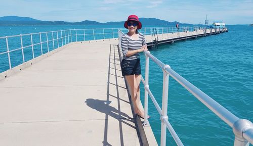 Young woman standing on boat sailing in sea against sky