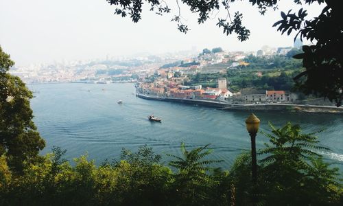 Boats in sea by cityscape against sky