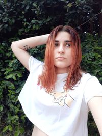 Portrait of young woman standing against plants