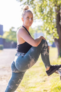 Portrait of young woman exercising on field