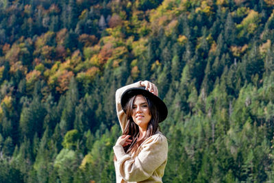 Portrait of woman standing against trees in forest