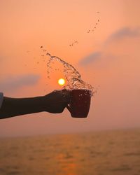 Silhouette bird flying over sea during sunset