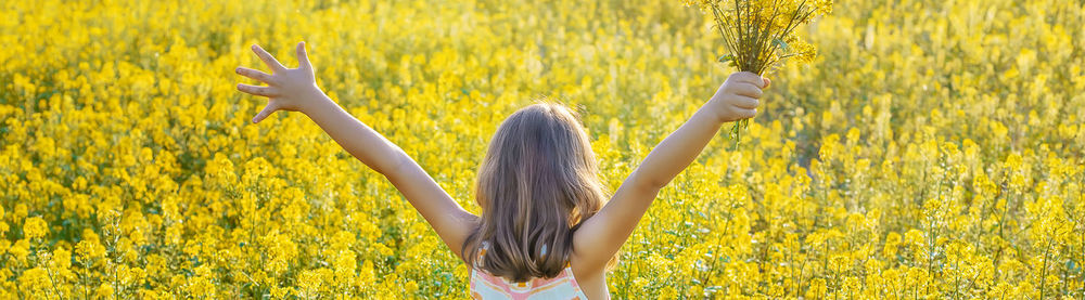 Girl with arms raised holding yellow flowers