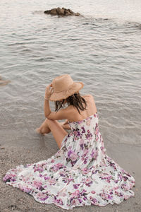 Rear view of woman sitting on beach