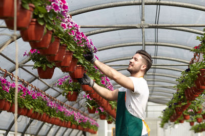 Young man and woman standing by potted plants