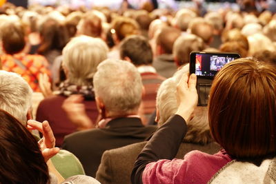 Rear view of woman photographing during concert