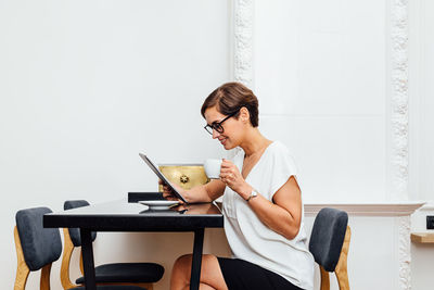 Side view of woman using digital tablet on table in cafe