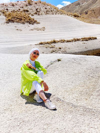 Full length of woman sitting on sand in desert