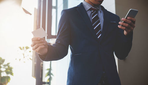 Midsection of businessman using mobile phone in office