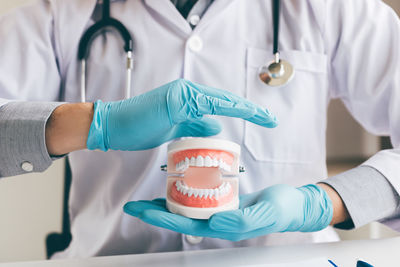 Midsection of male dentist holding denture