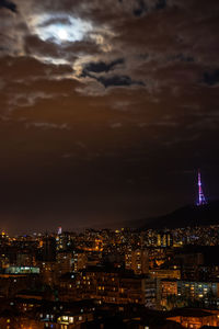 High angle view of illuminated buildings against cloudy sky