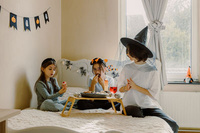 Three girlfriends eating halloween treats for breakfast in bed.