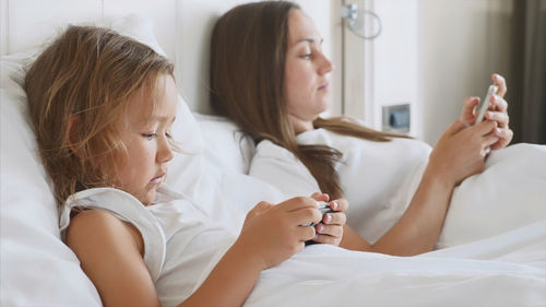 Friends looking away while relaxing on bed