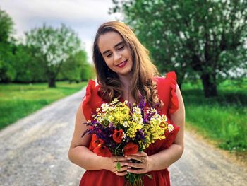 Young woman in red dress holding a bouquet of multicolored flowers