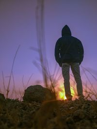 Rear view of man standing on field during sunset