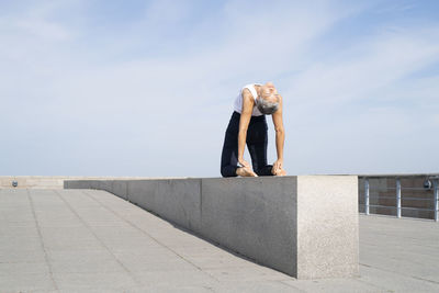Woman practicing yoga on pier