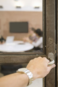 Businesswoman's hand opening door handle in creative office