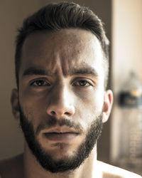 Close-up portrait of young man with beard at home