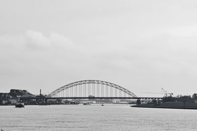 Bridge over river against cloudy sky