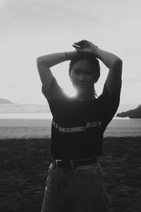 Portrait of woman standing at beach against sky