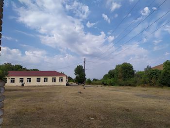 House on field by trees against sky