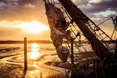 Sailboat on beach against sky during sunset