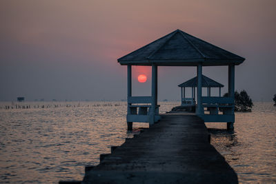 Lifeguard hut on beach against sky during sunset