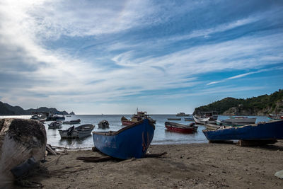 Boats moored on beach against sky