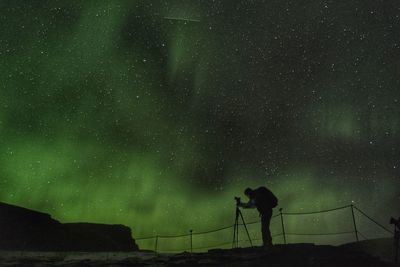 Silhouette man photographing against sky at night