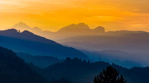 Scenic view of silhouette mountains against orange sky