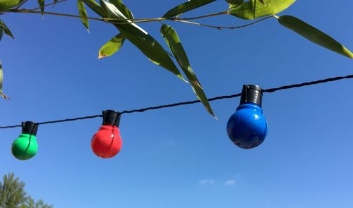 Low angle view of hanging lights against blue sky