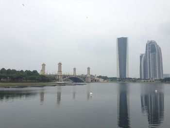 Modern buildings by lake against sky in city