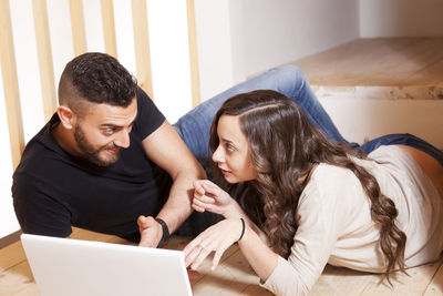 Side view of young woman using laptop at home