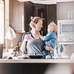 Portrait of smiling young woman using mobile phone at home