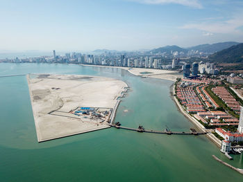 High angle view of city by sea against sky