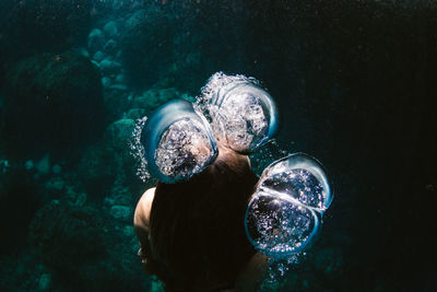 High angle of woman swimming underwater in sea amidst bubbles