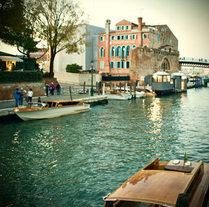 Boats in canal by buildings in city