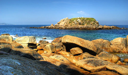 Scenic view of rocks on beach against clear sky