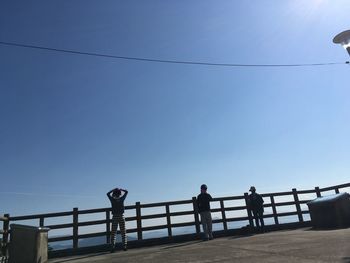 Low angle view of people walking on cables against clear sky