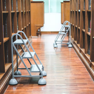 Ladders amidst bookshelves in library