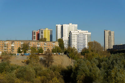 Buildings in city against clear blue sky