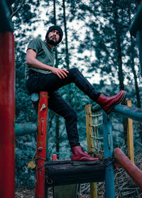 Young man sitting on seat in forest