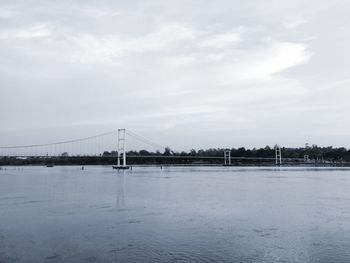 View of suspension bridge over water against sky