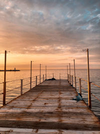 Pier over sea against sky during sunset